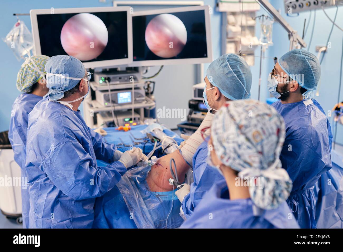 Professionnels qui surveillent la chirurgie sur un dispositif de surveillance lorsqu'ils sont en fonctionnement COVID-19 Banque D'Images