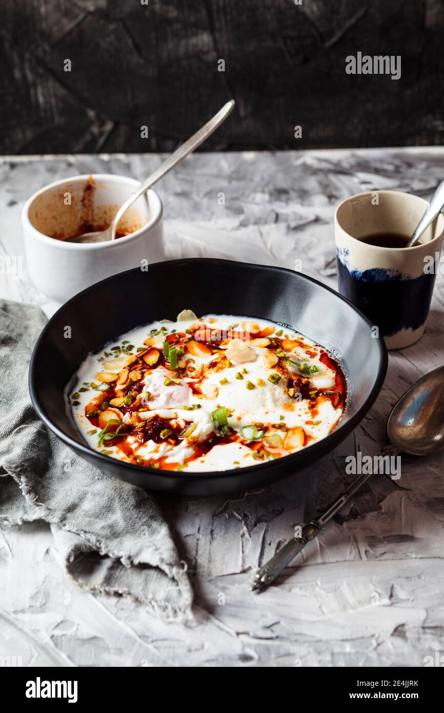 Petit-déjeuner composé d'œufs pochés, de yaourt et de beurre de paprika épicé dans un bol sur la table Banque D'Images