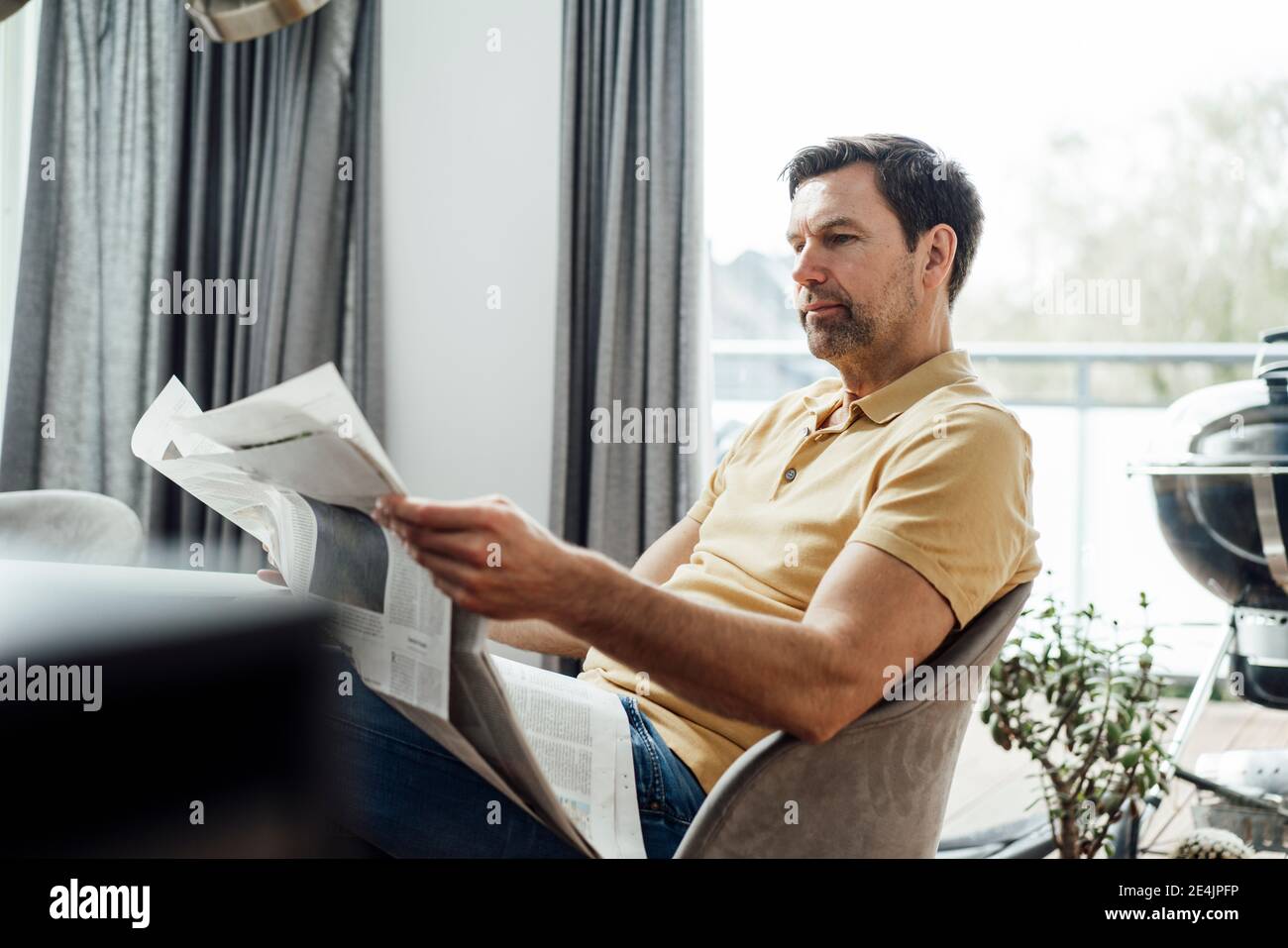 Homme mature lisant le journal dans le salon à la maison Banque D'Images