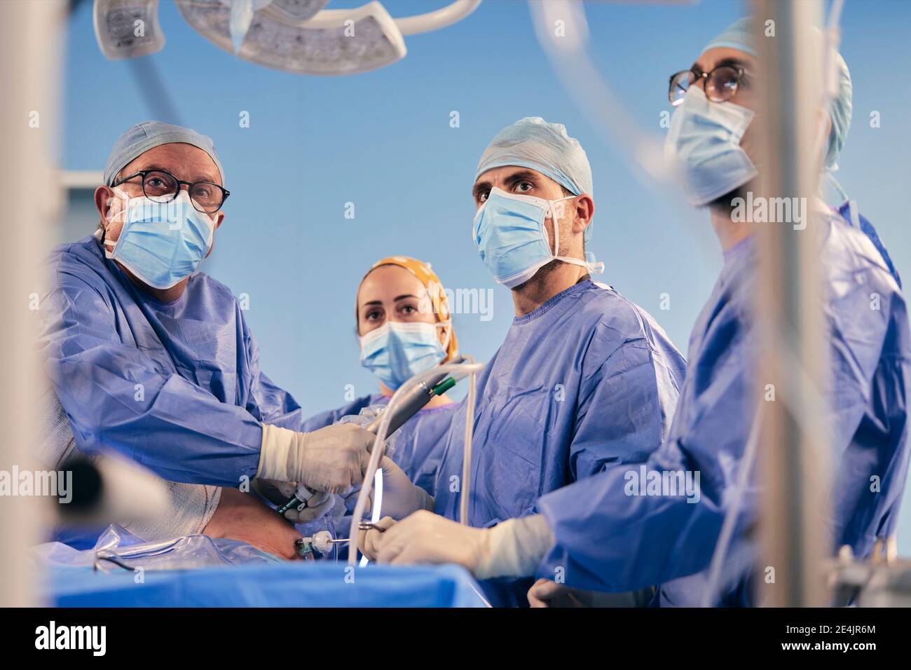 Professionnels avec l'équipement chirurgical d'endoscope faisant fonctionner la chirurgie pendant qu'ils sont debout Salle d'opération pendant COVID-19 Banque D'Images