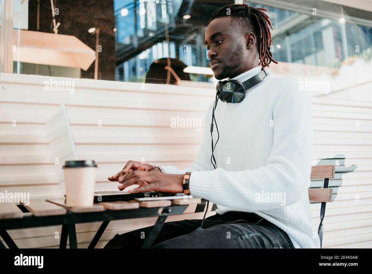 Homme d'affaires créatif avec une tasse à café jetable travaillant sur un ordinateur portable café Banque D'Images
