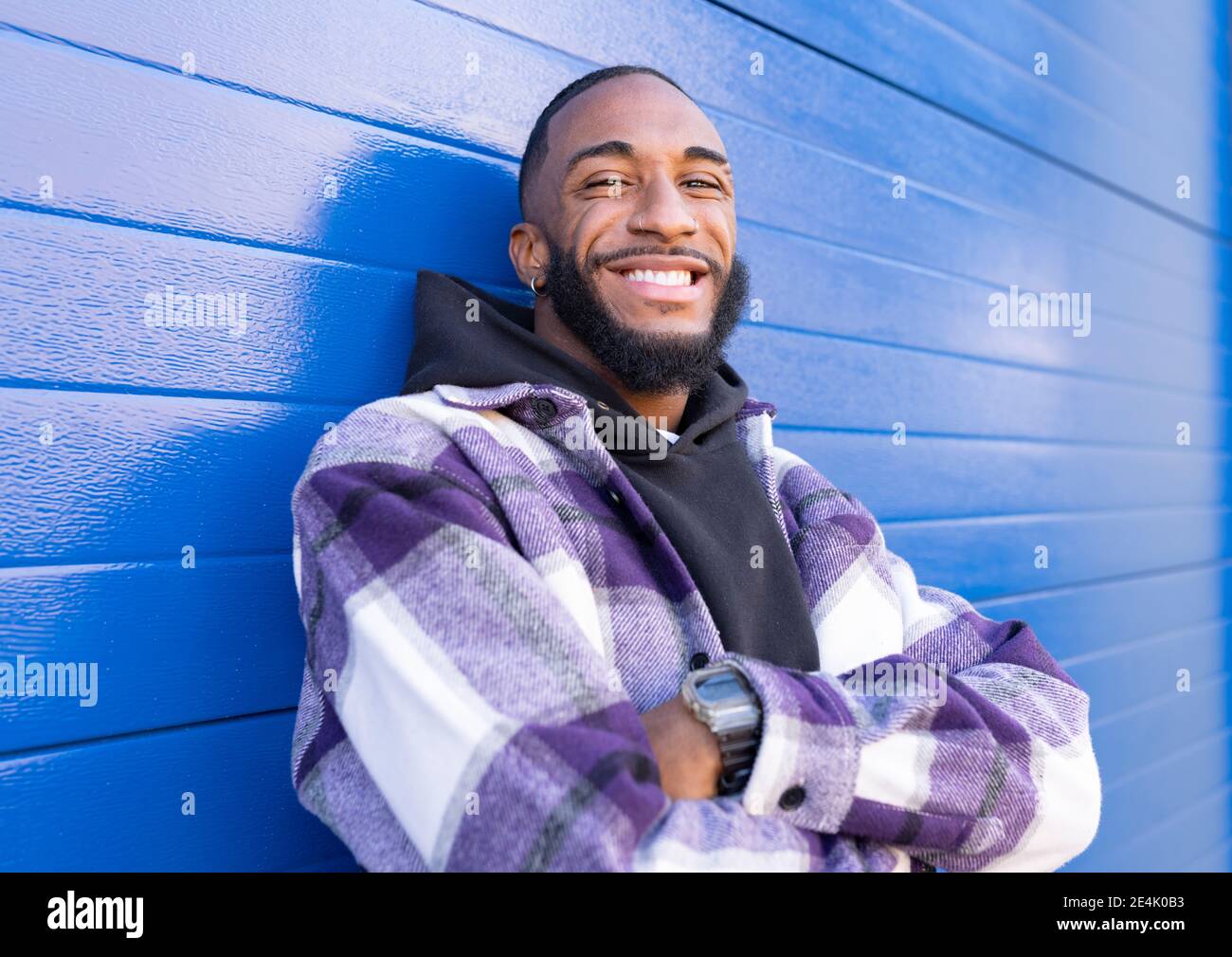 Un jeune rappeur mâle avec des bras croisés debout contre un carton ondulé  bleu mur Photo Stock - Alamy