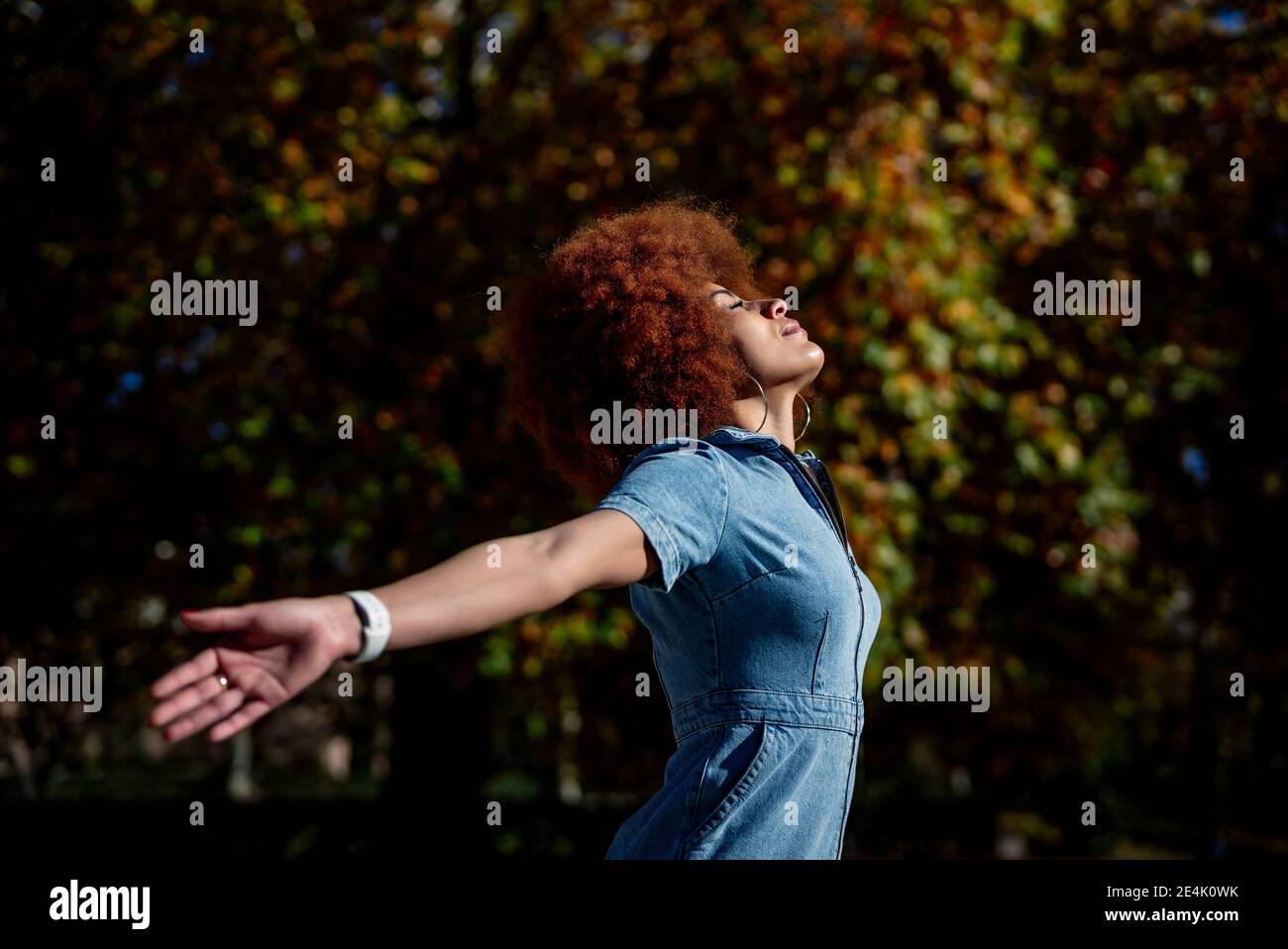 Femme adulte de taille moyenne avec bras étirés et yeux fermés à parc public Banque D'Images