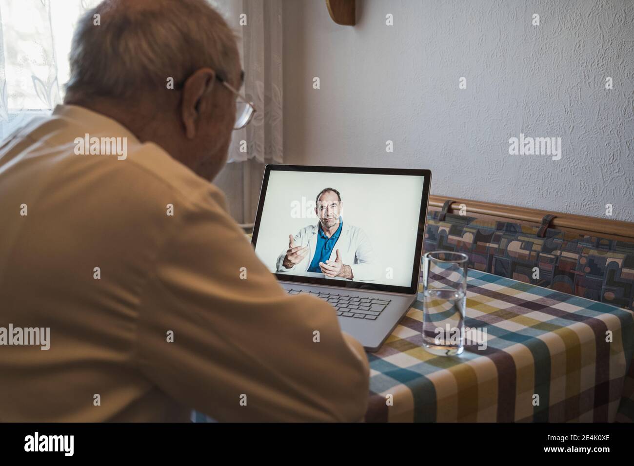 Homme senior prenant des conseils de médecin généraliste de sexe masculin par ordinateur portable lors d'un appel vidéo à la maison Banque D'Images