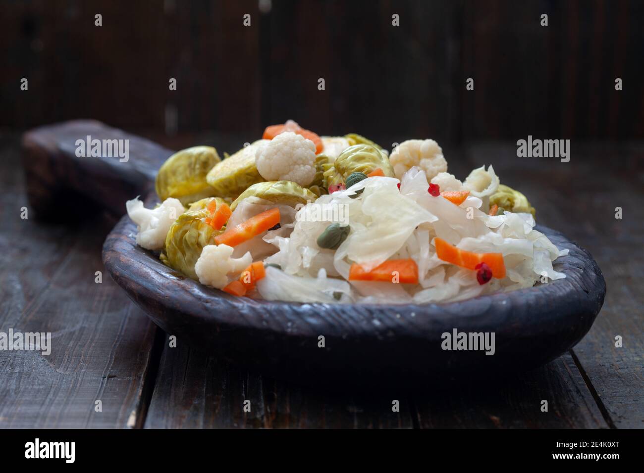 Légumes faits maison et piquetage de choucroute dans une assiette en bois rustique. Nourriture probiotique saine pleine de vitamines. Banque D'Images