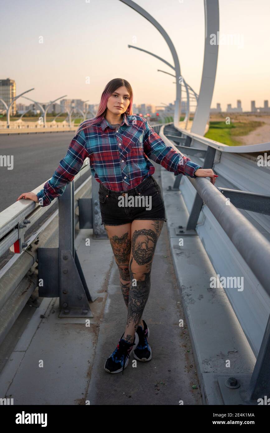 Jeune femme avec tatouage debout sur le pont par la route Banque D'Images