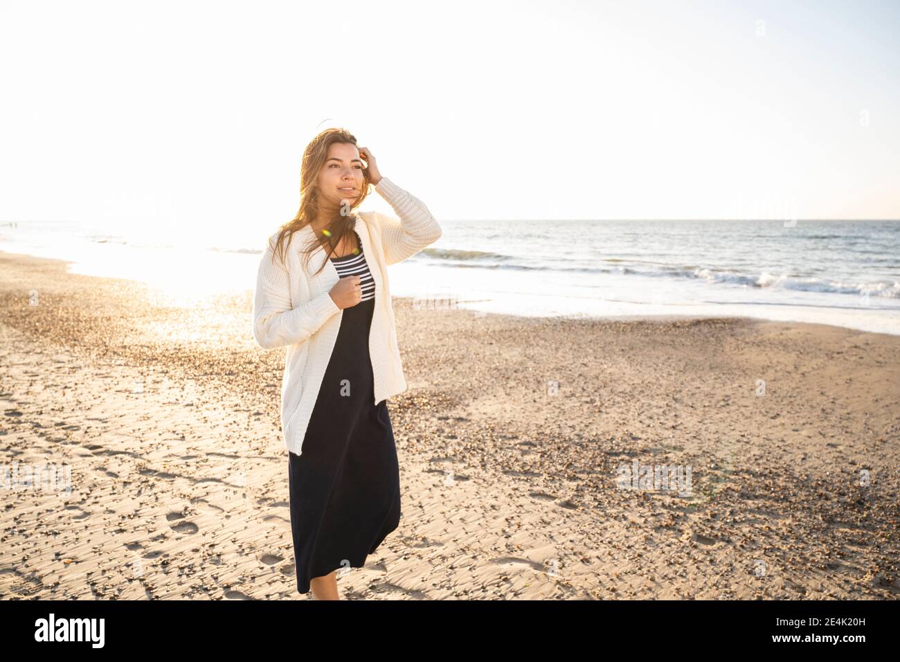 Jeune femme regardant loin en marchant à la plage sous le soleil jour Banque D'Images