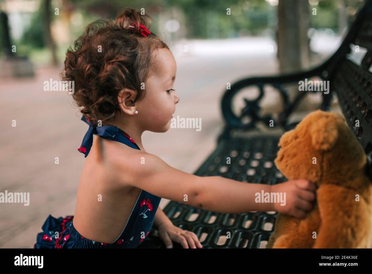 Gros plan de la petite fille qui joue avec l'ours en peluche banc dans le parc Banque D'Images