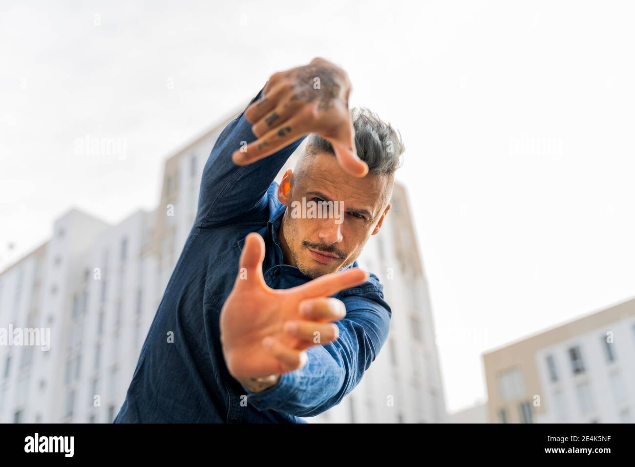 Beau homme faisant le cadre de doigt contre le ciel Banque D'Images