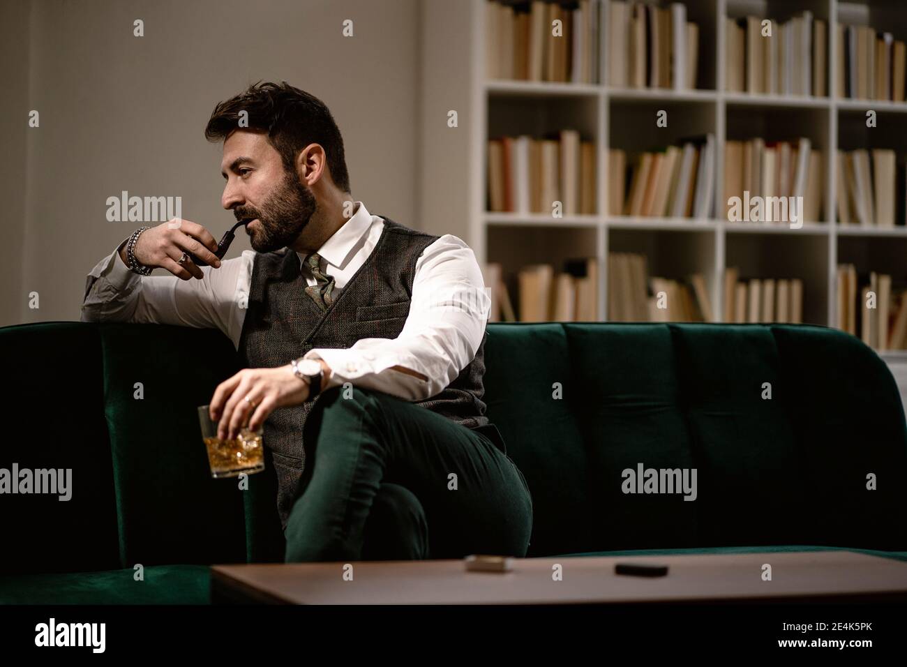 Portrait de l'homme barbu se reposant sur un canapé avec pipe à fumer et un  verre de whisky Photo Stock - Alamy