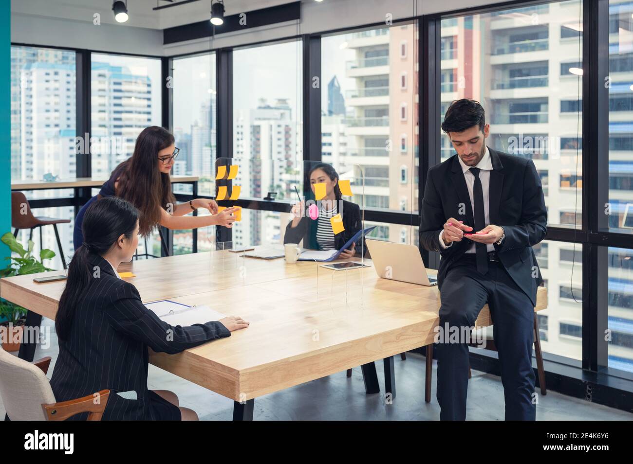 Équipe d'affaires multiethnique en brainstorming avec des post-it collés sur un tableau de conférence dans un espace de coworking dans le quartier des affaires Banque D'Images