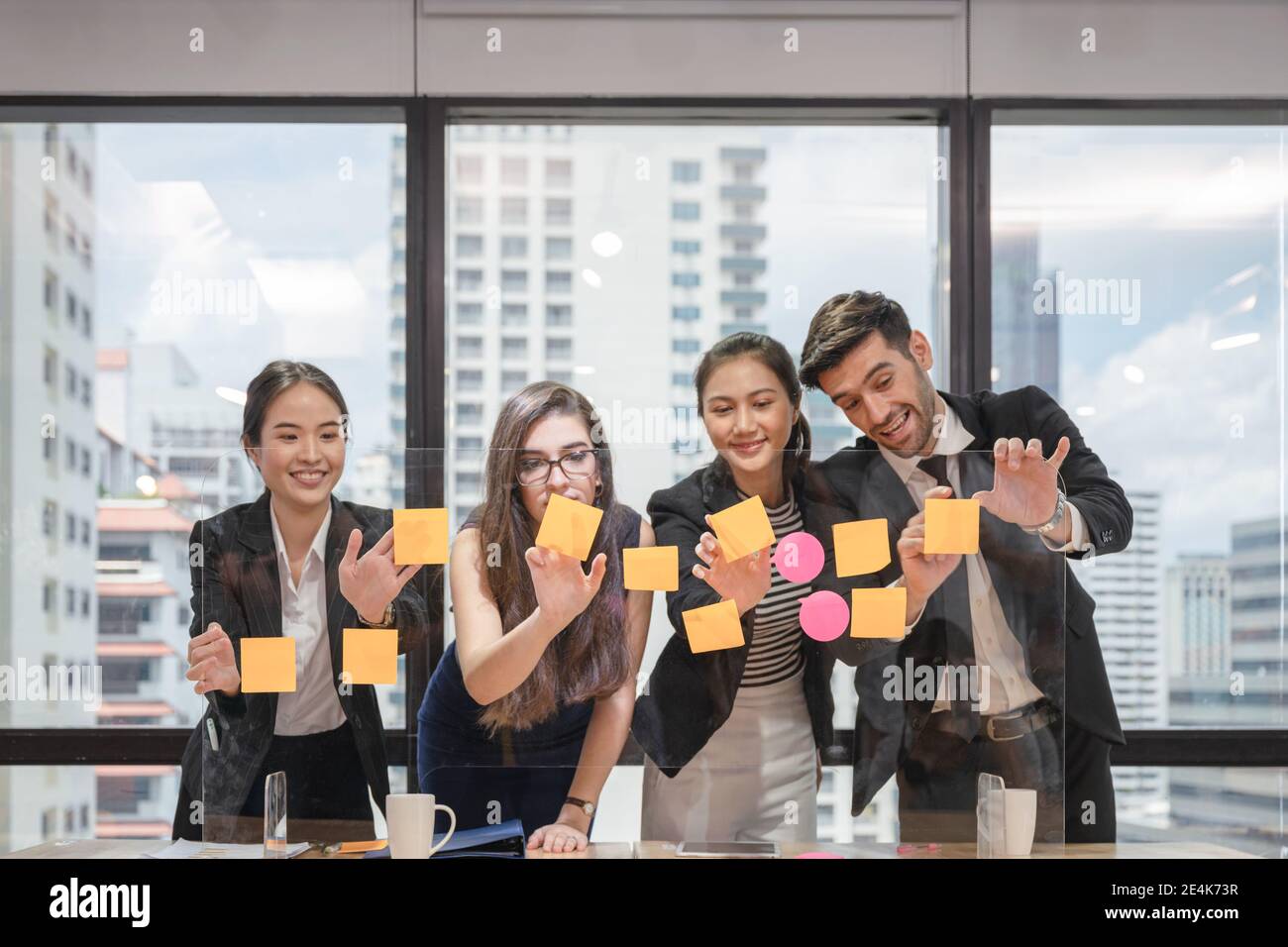 Équipe d'affaires multiethnique en brainstorming avec des post-it collés sur un tableau de conférence dans un espace de coworking dans le quartier des affaires Banque D'Images