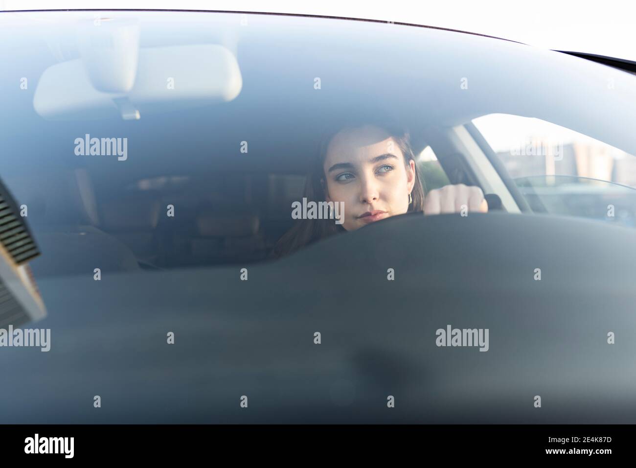 Jeune femme d'affaires qui regarde loin en étant assise en voiture Banque D'Images