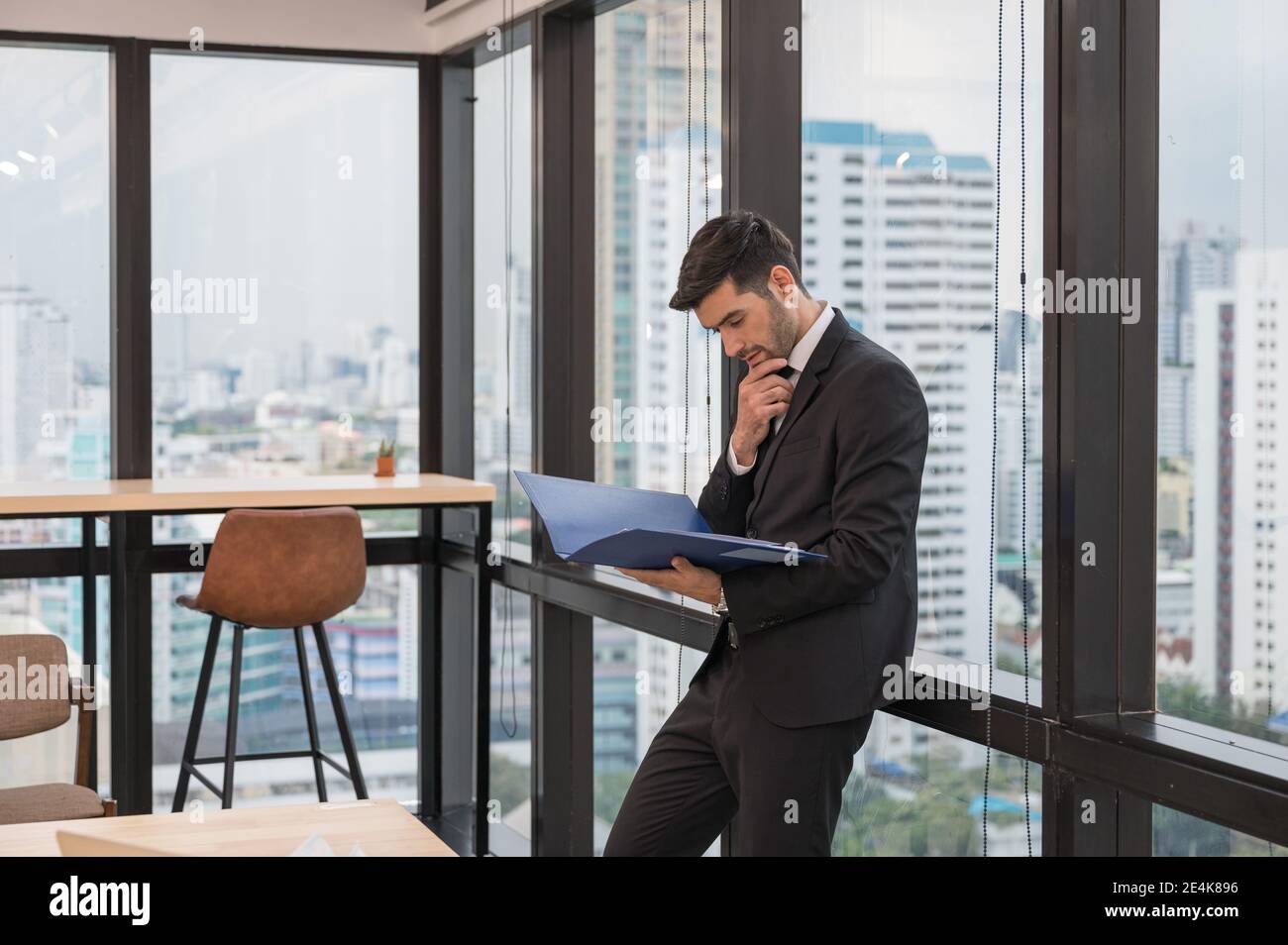 Homme d'affaires caucasien en procès avec la tenue de la paperasserie et l'analyse de plan d'affaires dans le bureau moderne Banque D'Images