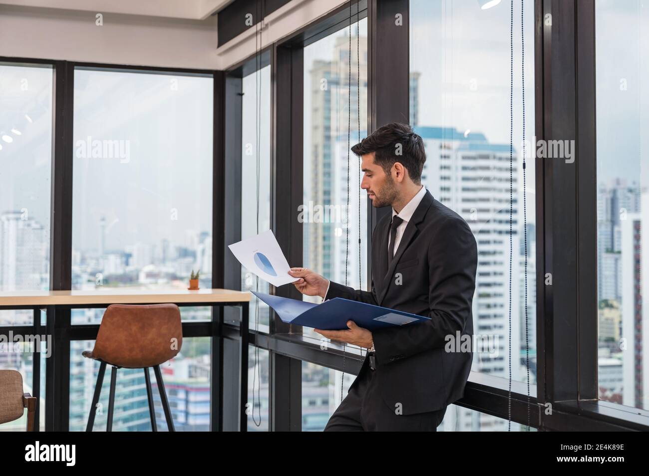 Homme d'affaires caucasien en procès avec la tenue de la paperasserie et l'analyse de plan d'affaires dans le bureau moderne Banque D'Images