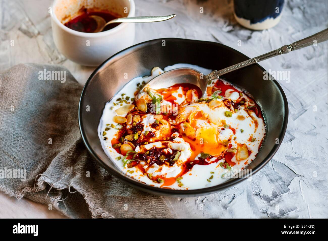 Gros plan du yaourt et du beurre de paprika épicé sur les œufs pochés dans un bol sur la table Banque D'Images