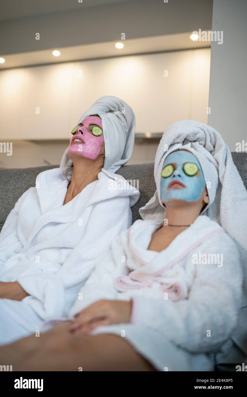 Mère et fille avec des masques faciaux relaxant dans la vie Banque D'Images