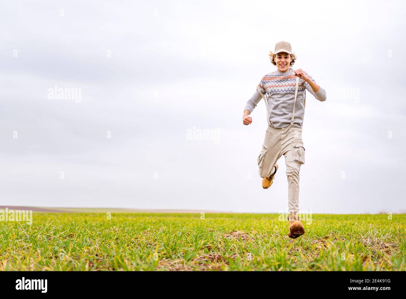 Jeune homme qui court vers l'appareil photo sur un terrain herbeux Banque D'Images