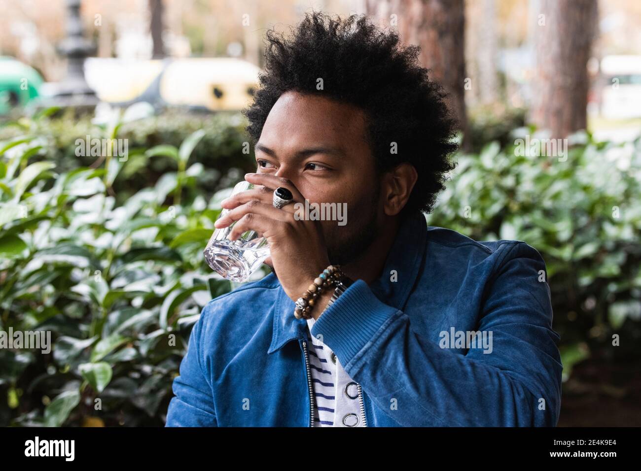Gros plan d'un homme adulte moyen avec de l'eau potable pour cheveux afro au café extérieur Banque D'Images