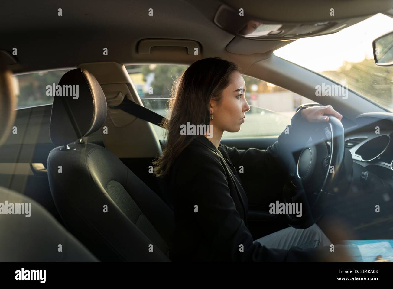 Jeune femme d'affaires regardant loin en conduisant la voiture Banque D'Images