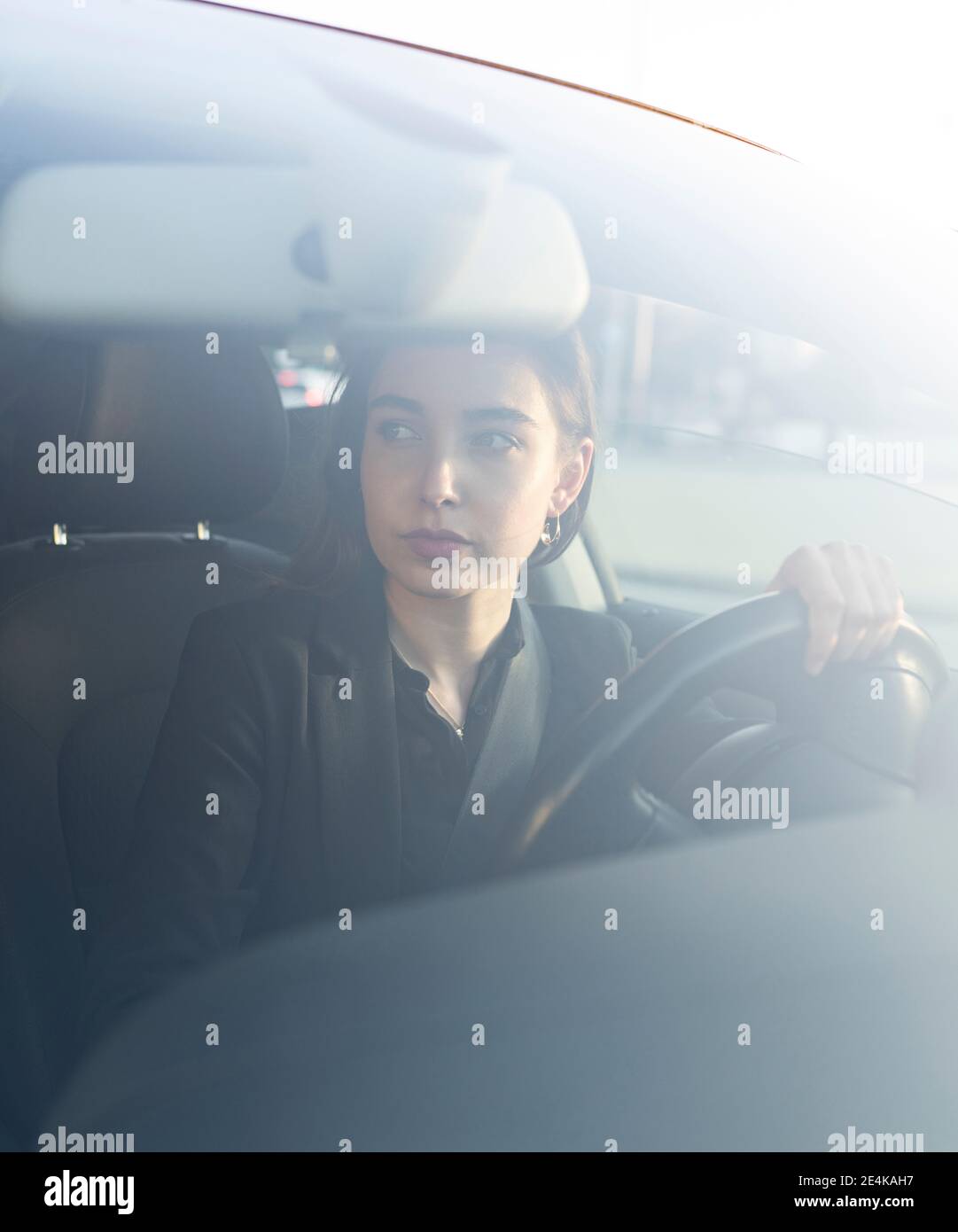 Femme d'affaires regardant loin en étant assise dans la voiture Banque D'Images