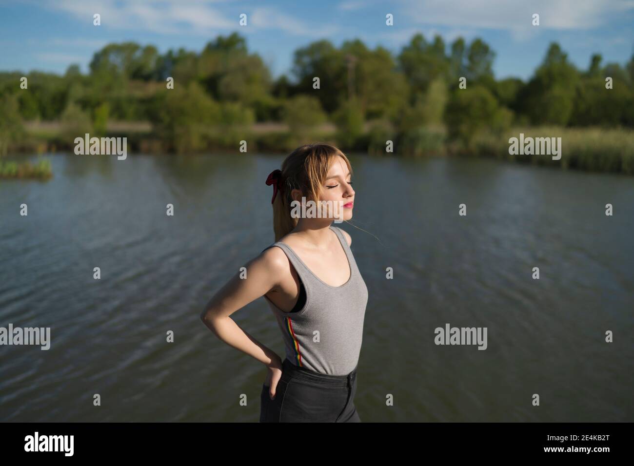 Belle femme debout avec les mains dans les poches au bord du lac Banque D'Images