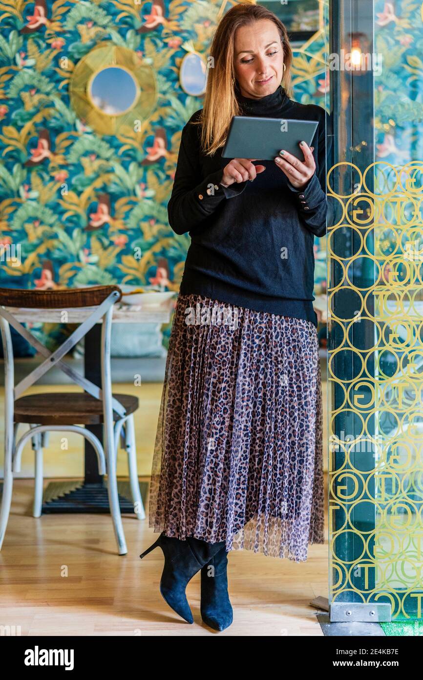 Portrait d'une blonde aux cheveux longs debout dans un restaurant avec tablette numérique entre les mains Banque D'Images