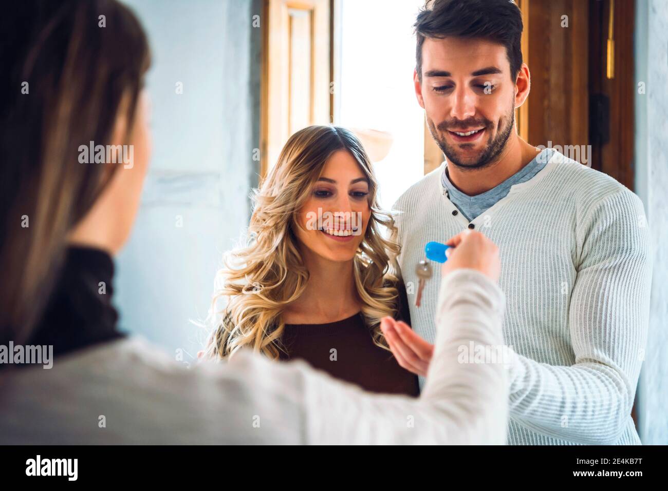 Agent immobilier remettant les clés à un jeune couple heureux Banque D'Images Agent immobilier remettant les clés à un jeune couple heureux Banque D'Images