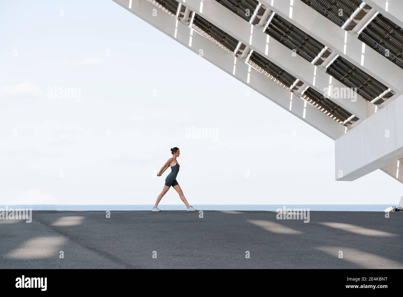 Sportswoman faisant de l'exercice d'échauffement contre le ciel clair Banque D'Images