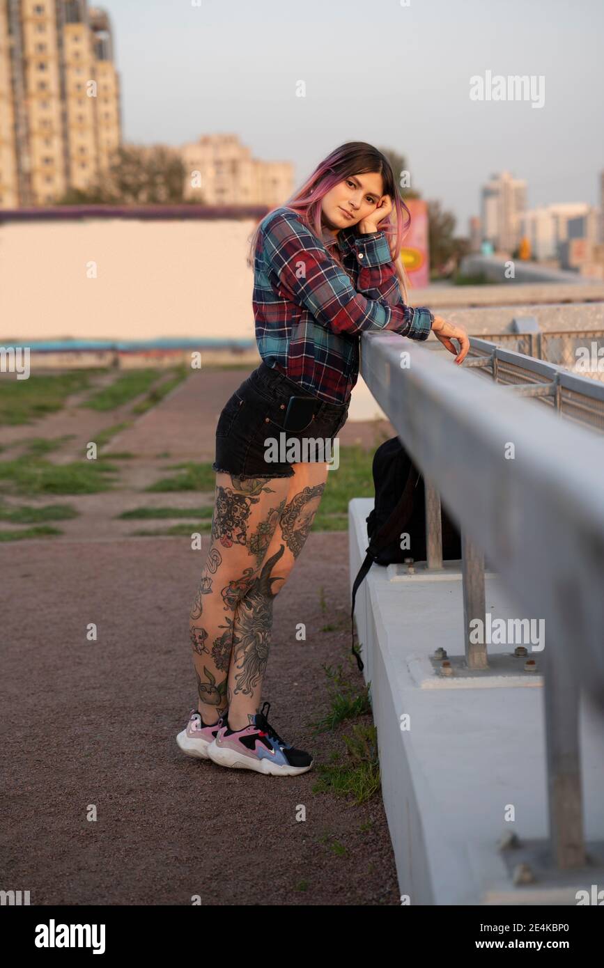 Jeune femme tattoo penchée sur la rampe sur le toit Banque D'Images