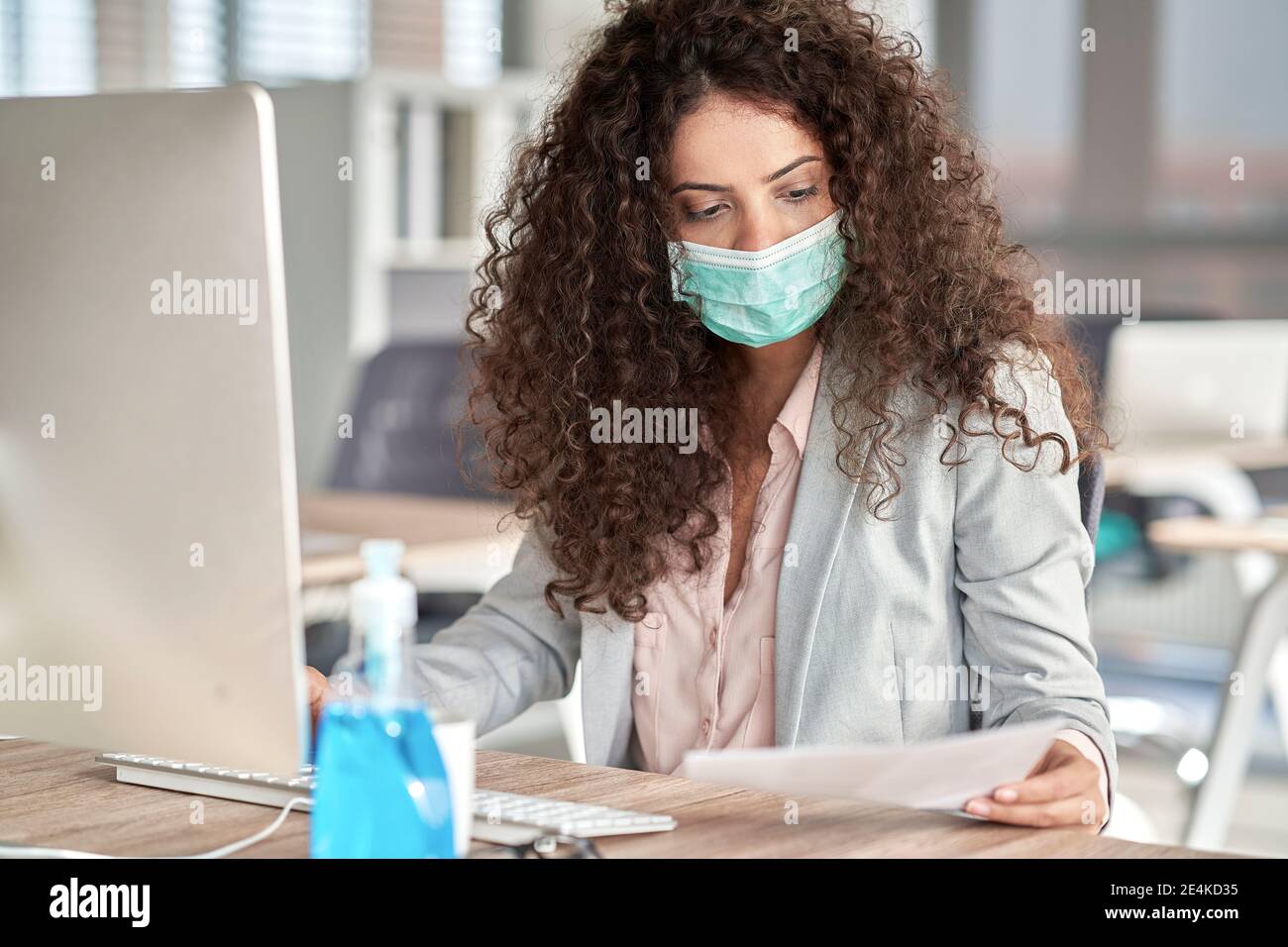 Une femme professionnelle examine un document papier pendant qu'elle travaille sur un bureau pendant la COVID-19 Banque D'Images