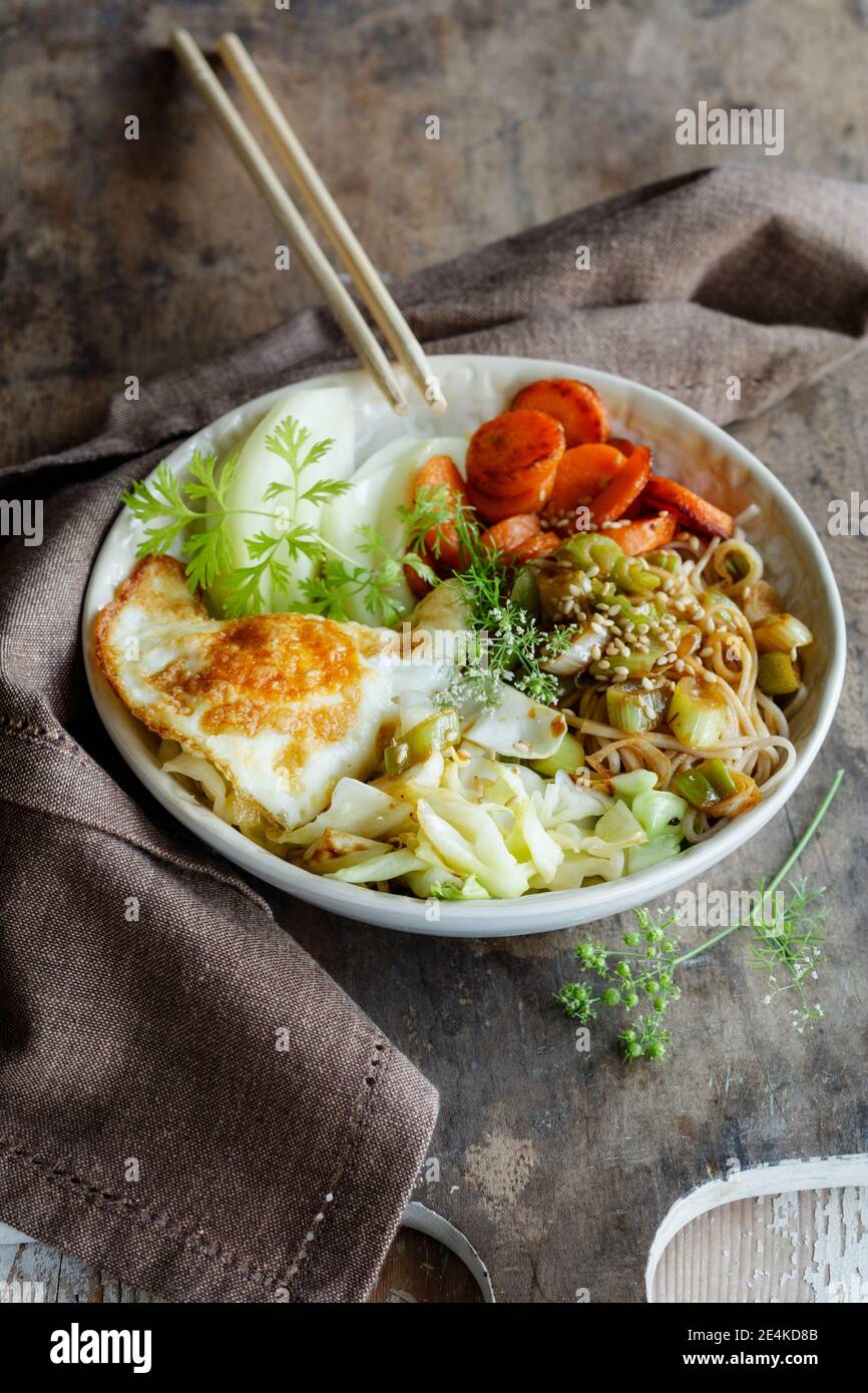 Bol de nouilles soba avec chou, carottes, chou-rave, œuf frit et herbes Banque D'Images