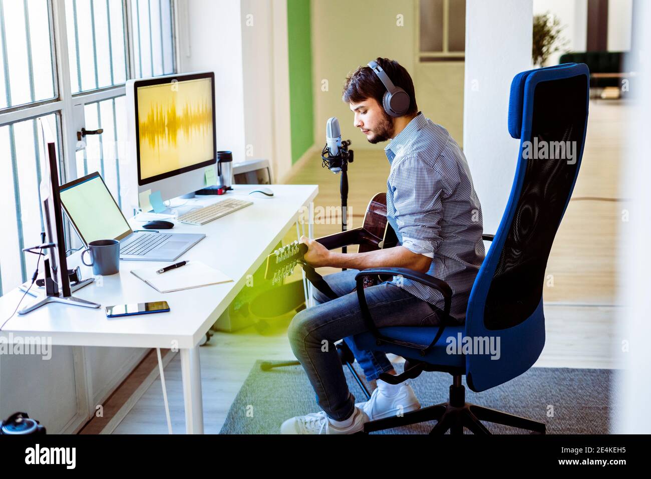 Musicien enregistrant de la musique en étant assis dans un studio d'enregistrement Banque D'Images