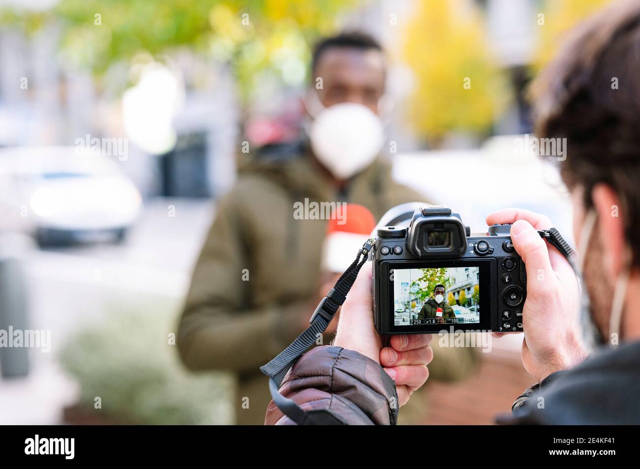 Gros plan d'un opérateur de sexe masculin filmant un journaliste avec caméra Banque D'Images