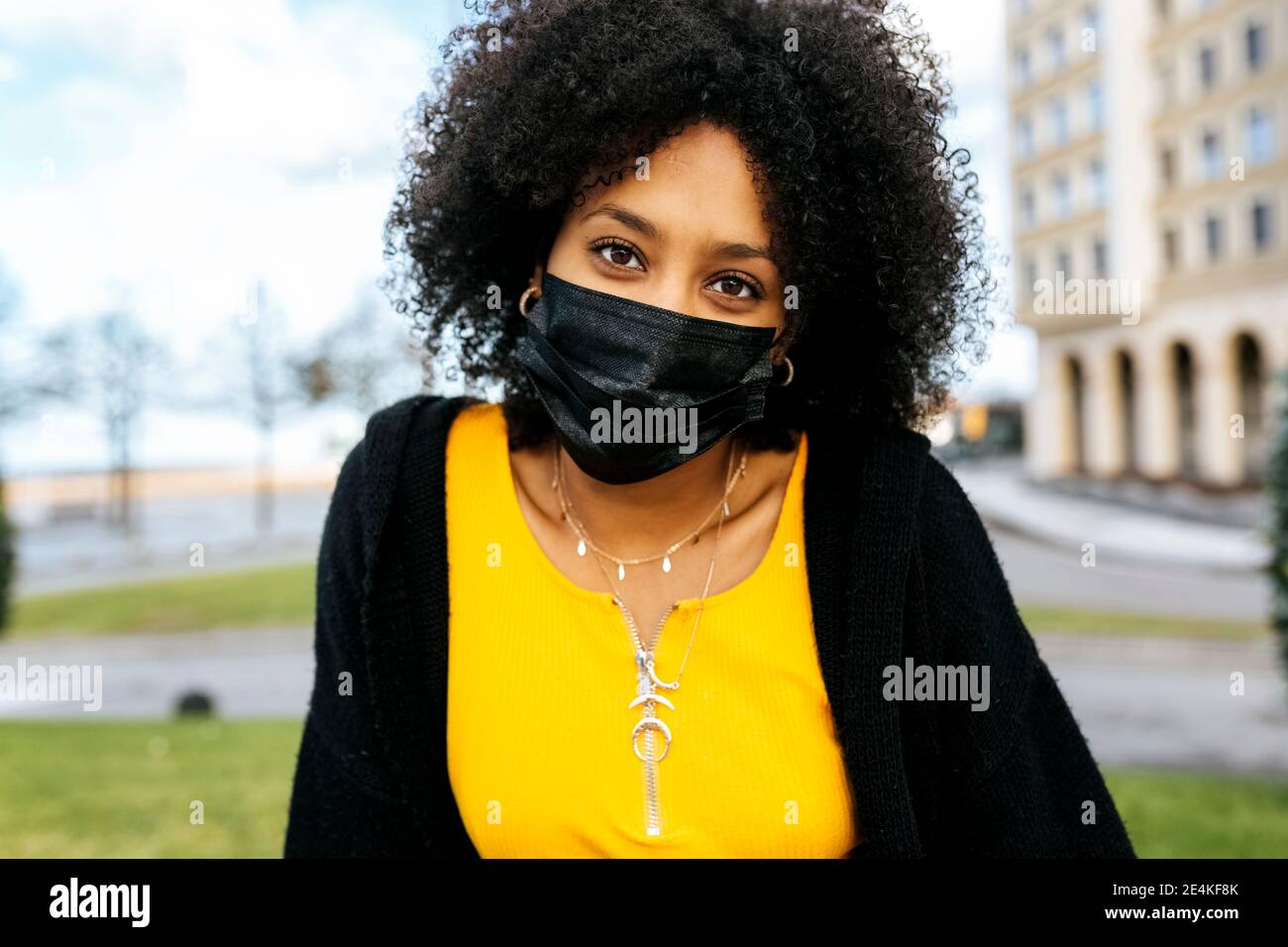 Gros plan de la jeune femme avec des cheveux afro portant un visage noir masque Banque D'Images