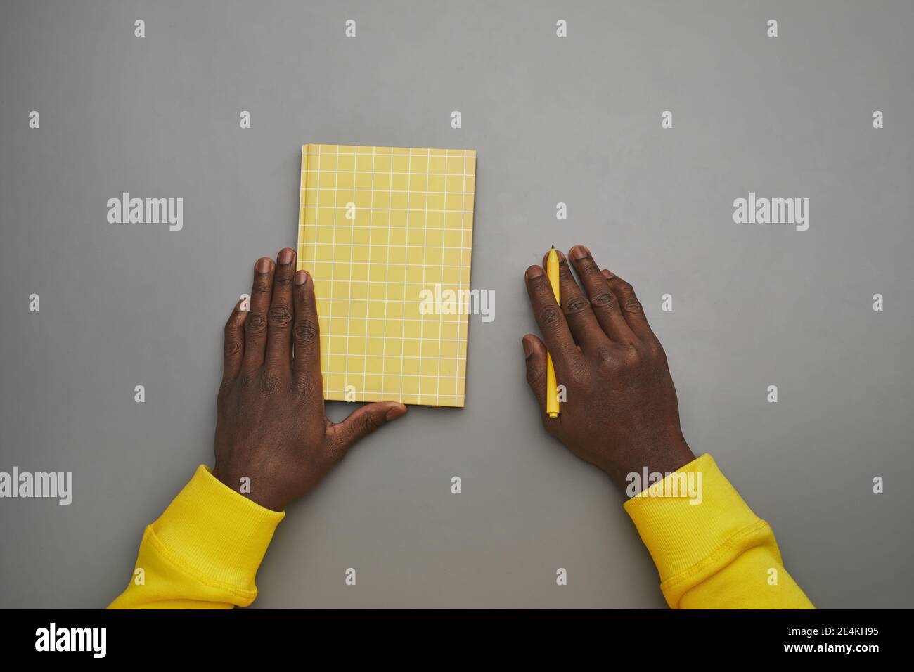 Arrière-plan gris minimal de mains afro-américaines de sexe masculin tenant un carnet ou un journal au bureau, vue de haut en bas, espace de copie Banque D'Images