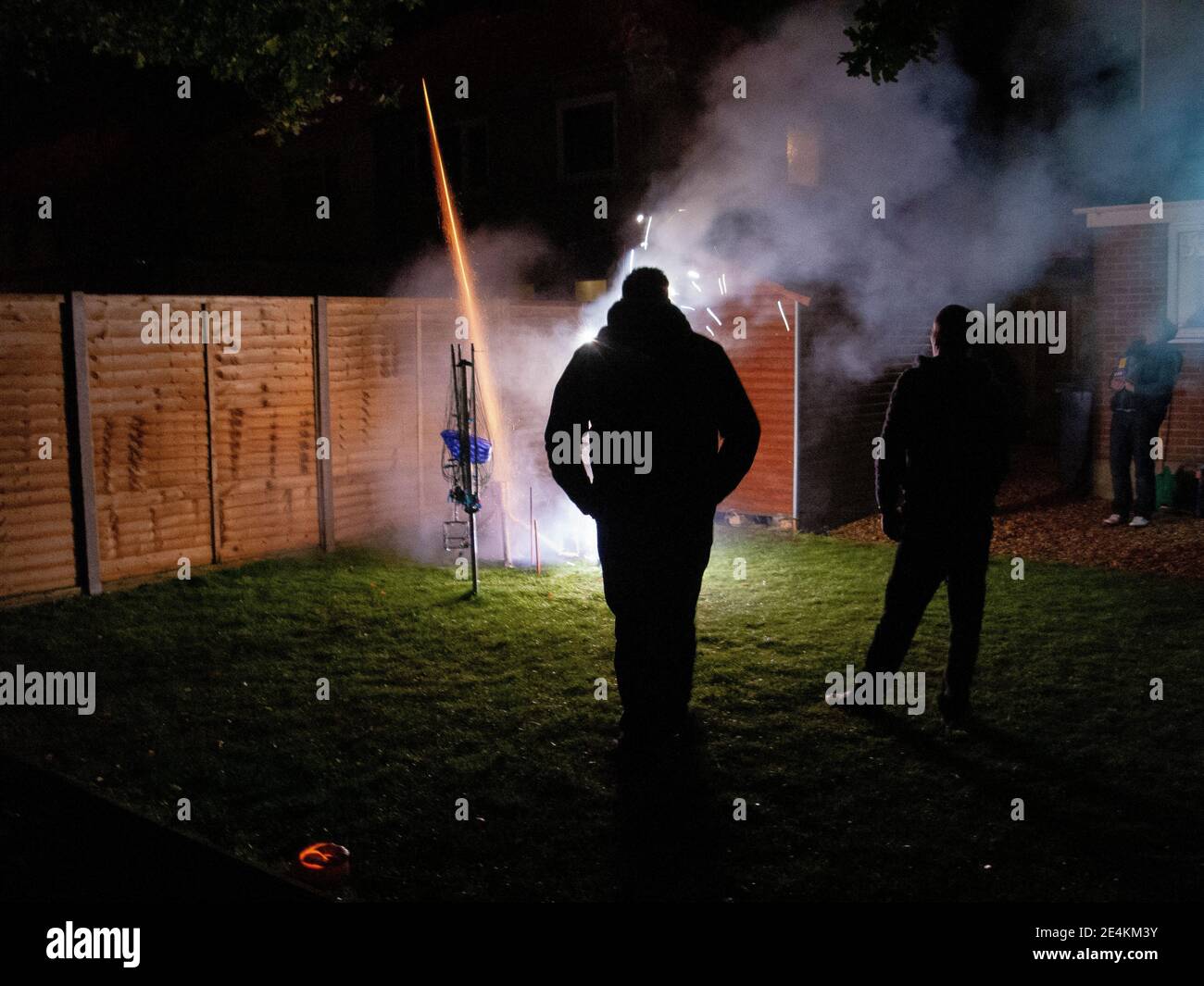 Deux hommes regardent un tir de fusée lancé d'un tube dans un jardin arrière de banlieue à l'époque de la nuit de Guy Fawkes à Bournemouth, Dorset. 04 novembre 2012. Photo: Neil Turner Banque D'Images