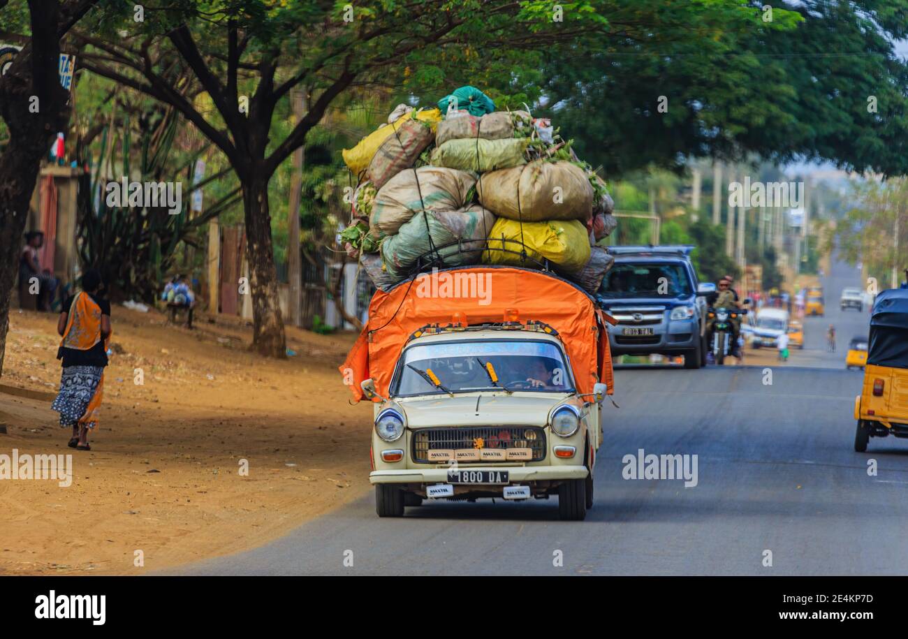 La voiture surchargée se déplace sur la route asphaltée à travers un africain village Banque D'Images