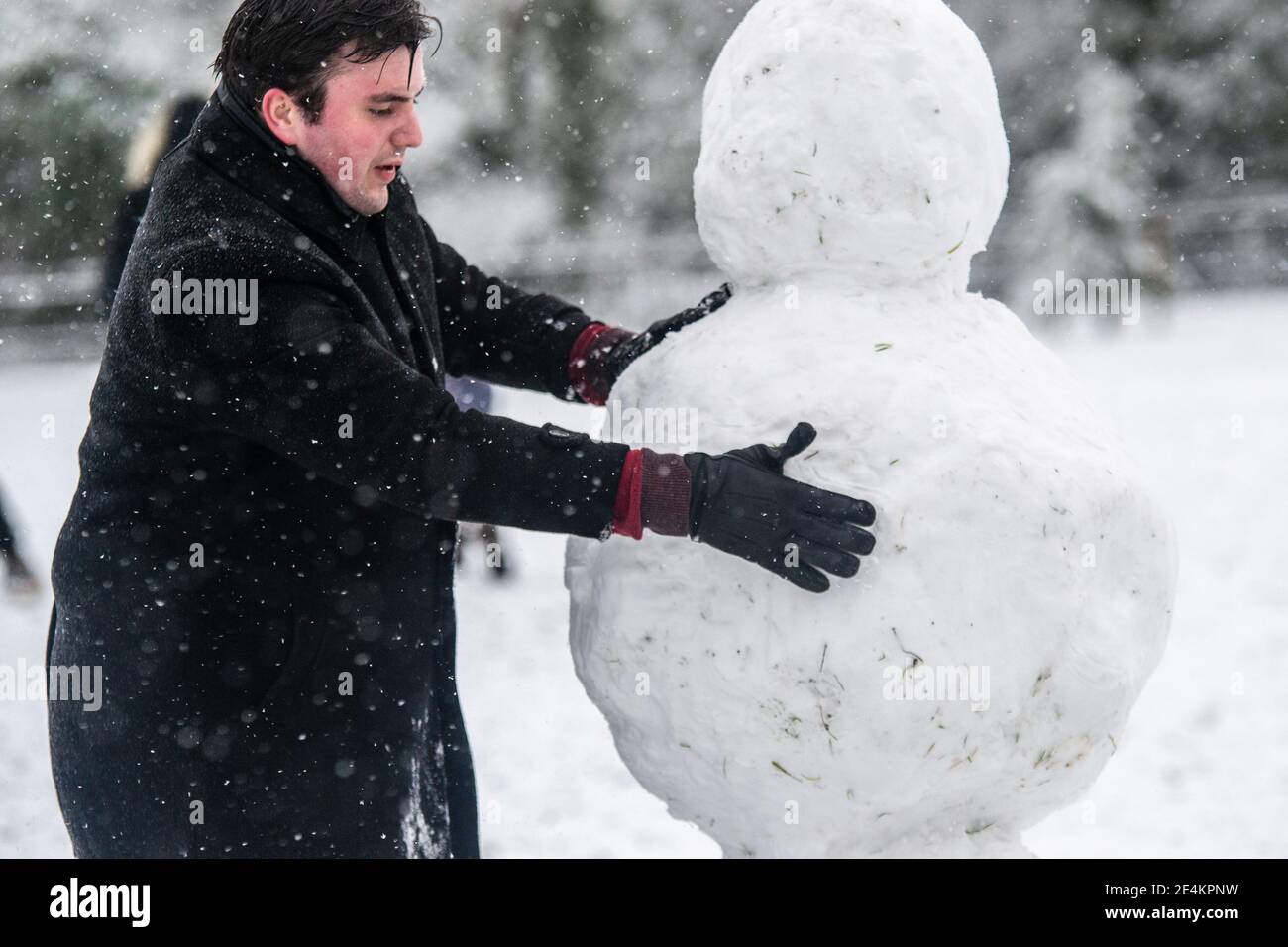 Leamington Spa, Warwickshire, Royaume-Uni: 24 janvier 2021: Les fêtards se réchauffent pour construire des bonhommes de neige dans le parc Victoria, comme un grand groupe de neige peint le pays blanc le dimanche matin. Credit: Ryan Underwood / Alamy Live News Banque D'Images