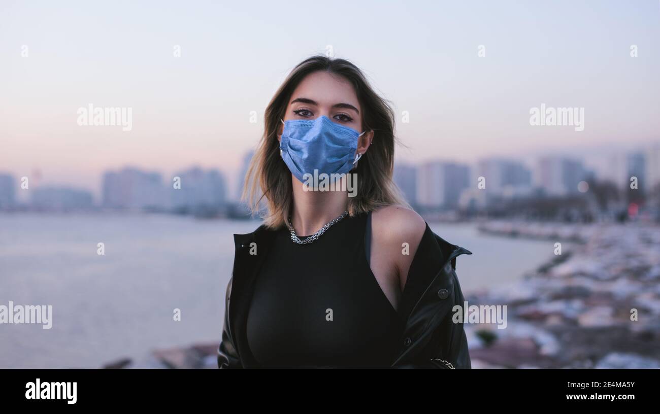 Portrait d'une adolescente avec un masque médical dans la rue et regardant l'appareil photo. Banque D'Images