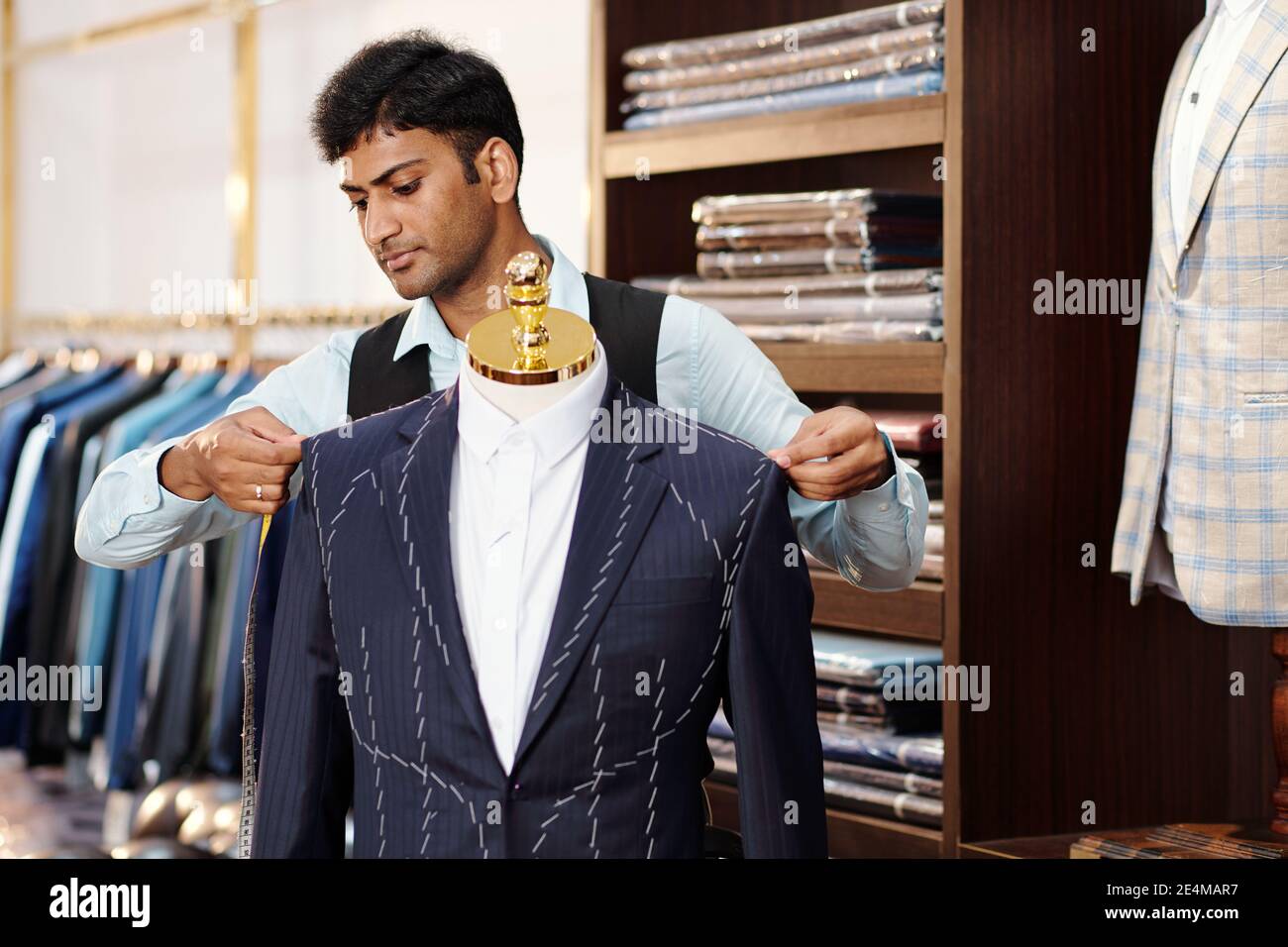 Sérieux talentueux jeune Indien tailleur vérifier veste sur mesure sur mannequin lorsque vous travaillez sur suit pour le client Banque D'Images