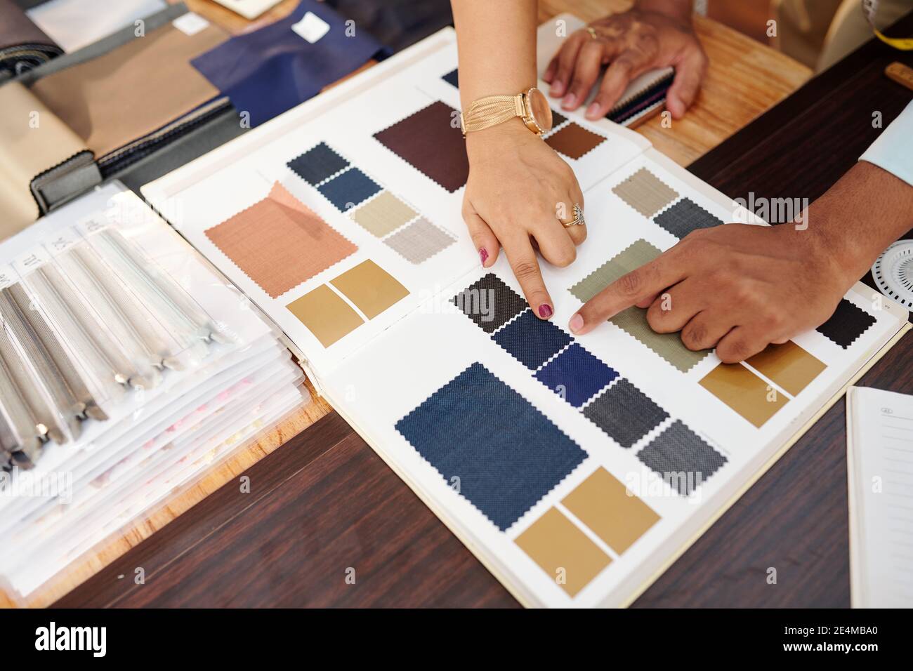 Mains de tailleur et client choisissant le tissu du catalogue pour pour un costume sur mesure Banque D'Images