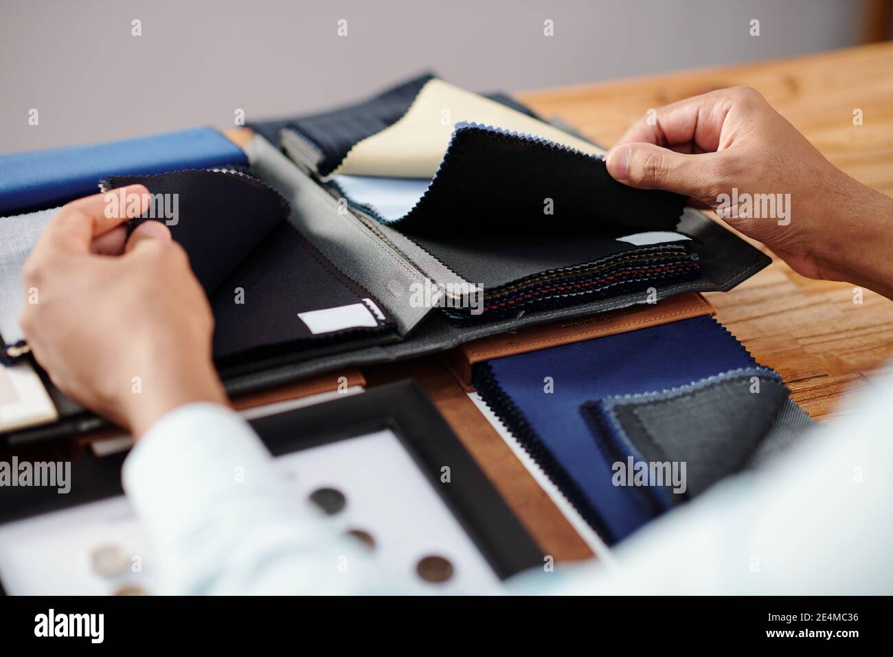 Mains de tailleur touchant deux types de tissu de laine noire pour choisir un costume sur mesure Banque D'Images