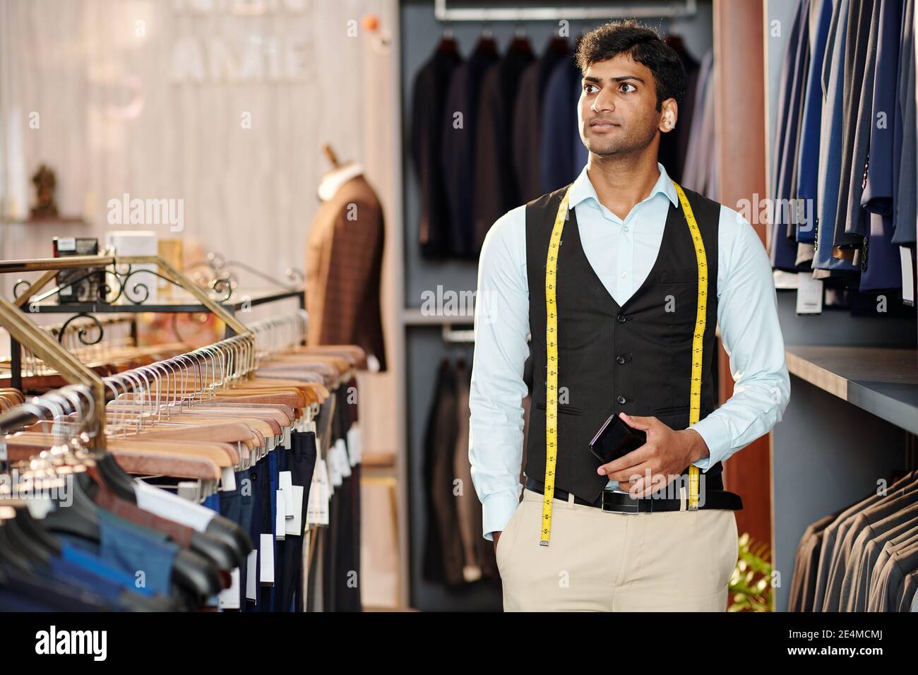 Jeune directeur des ventes indien avec mètre ruban travaillant en homme magasin de vêtements Banque D'Images