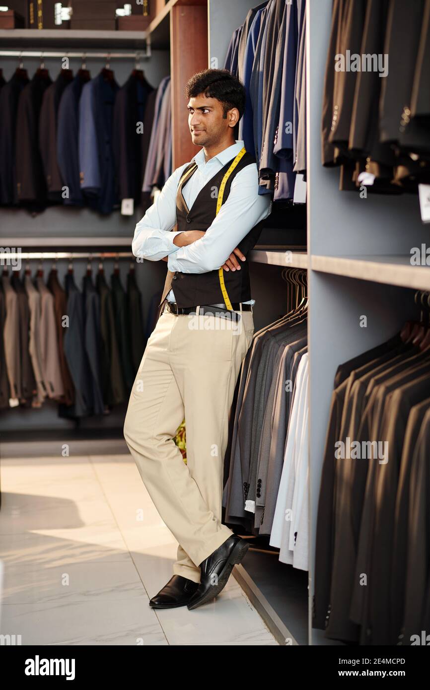 Assistant-boutique avec ruban de mesure vendant des costumes, des vestes et des pantalons pour hommes en magasin Banque D'Images