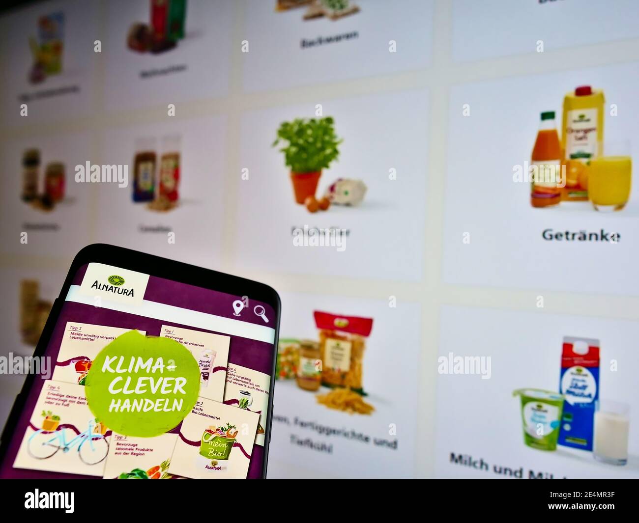 Smartphone avec logo de la chaîne allemande de supermarchés d'aliments biologiques Alnaturaa Produktions- und Handels GmbH sur écran avec des produits. Mise au point sur l'affichage du téléphone. Banque D'Images