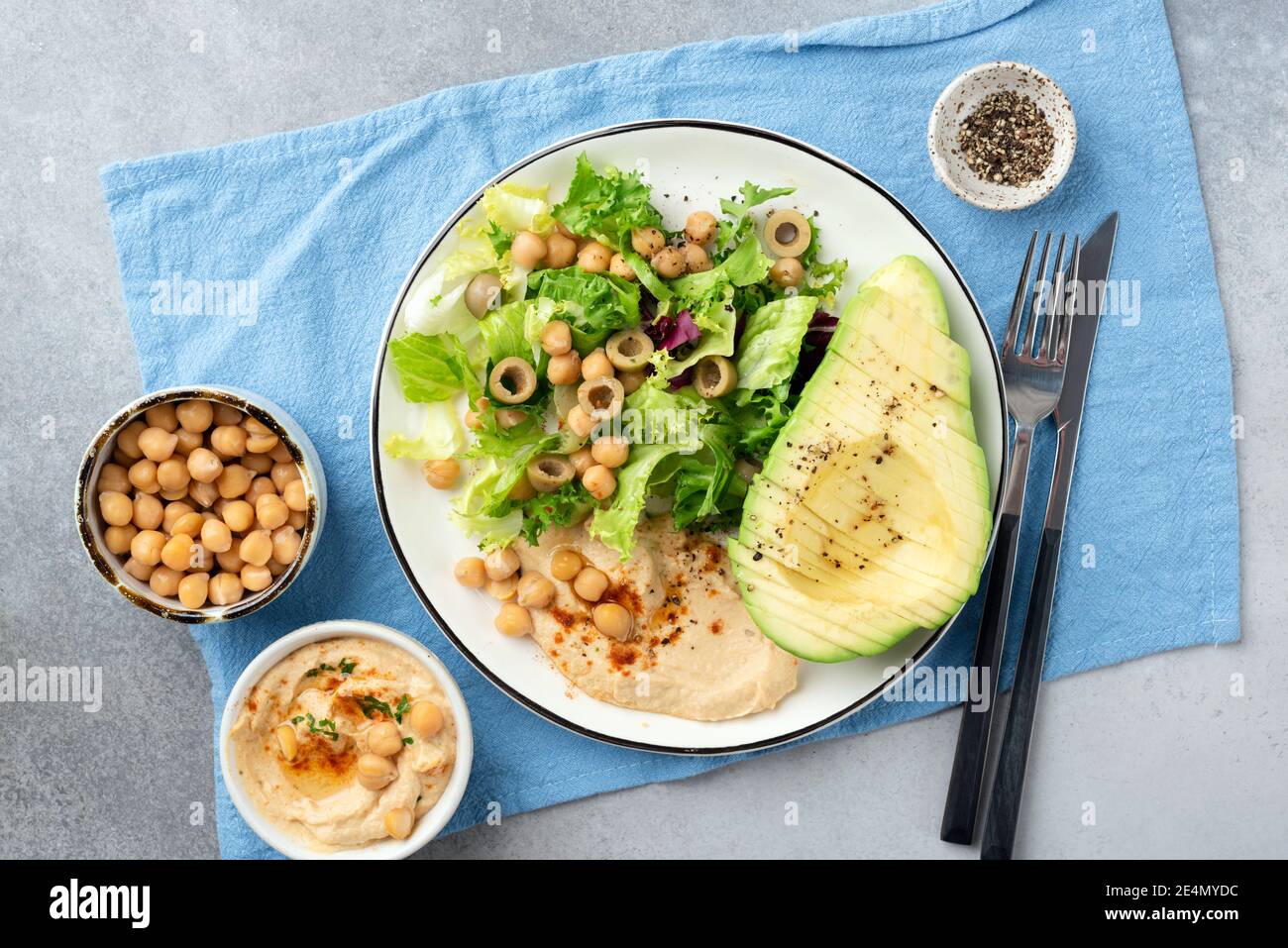 Salade végétalienne saine avec avocat, houmous de pois chiches, légumes verts et olives. Vue de dessus. Manger propre, manger, désintoxication concept alimentaire Banque D'Images