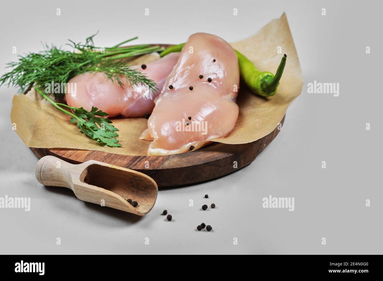 Filets de poulet crus sur une assiette en bois avec une cuillère Banque D'Images