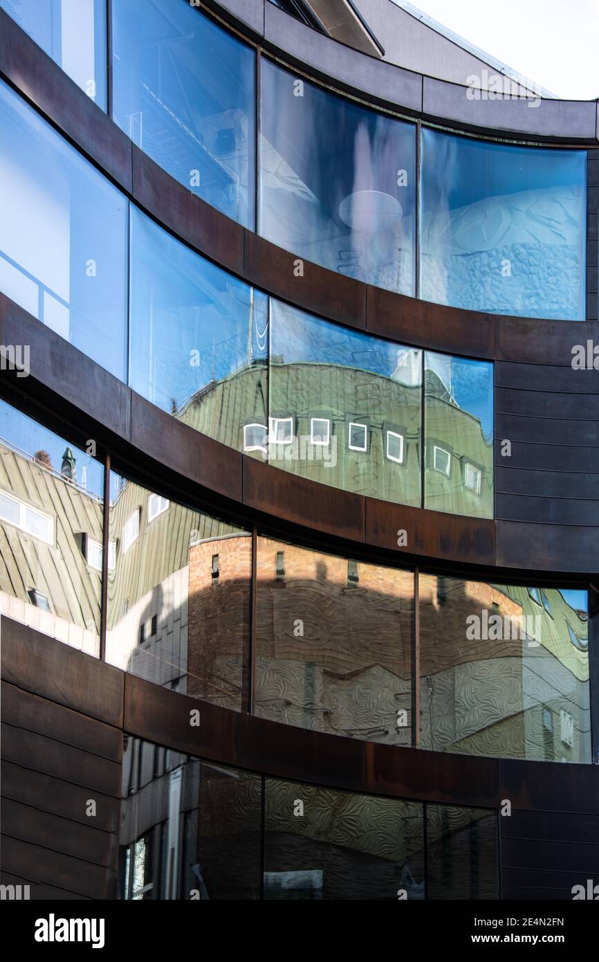 Extérieur du bâtiment avec de grandes fenêtres reflétant d'autres bâtiments et le ciel bleu Banque D'Images