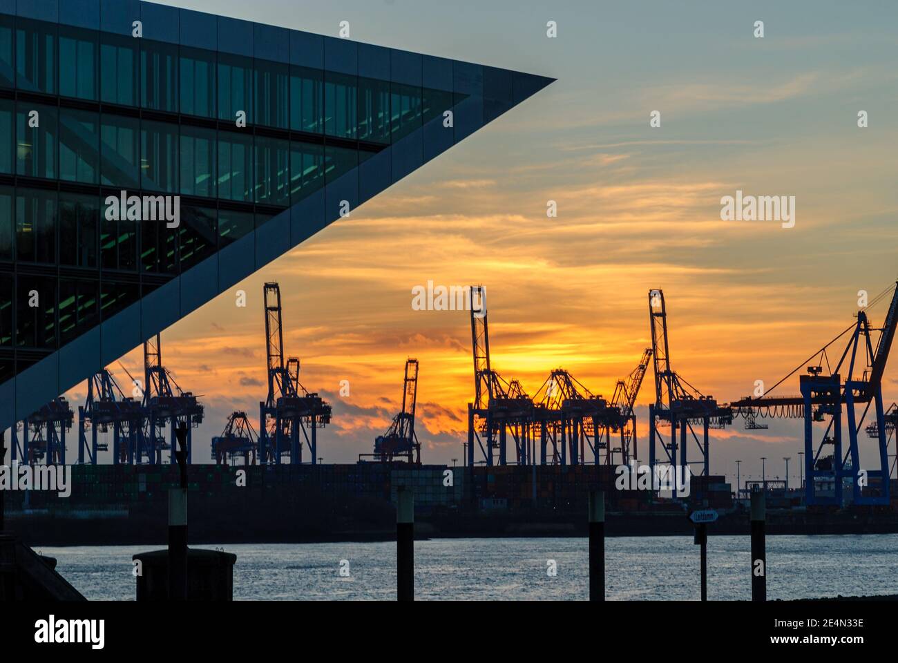 Port de Hambourg, Allemagne : silhouettes de grues au coucher du soleil par temps nuageux Banque D'Images